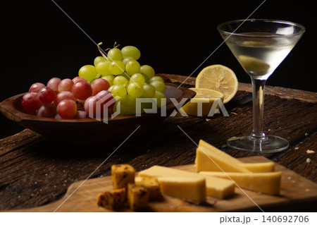 Appetizers board featuring cheeses, grapes, olives, and a drink, creating a sophisticated still life of gourmet food, perfect for wine tasting and gatherings Appetizers board featuring cheeses, grapes, olives, and a drink, creating a sophisticated still life of gourmet food, perfect for wine tasting and gatherings 140692706
