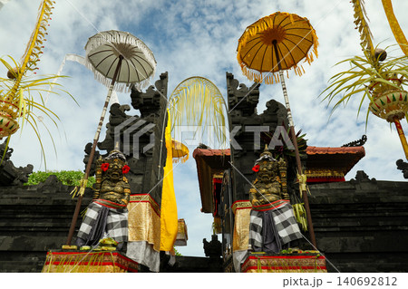 Balinese sculptures greet at temple with bright umbrellas Balinese sculptures greet at temple with bright umbrellas 140692812