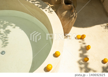 A circular stone bath is adorned with vibrant lemons and clay pots A circular stone bath is adorned with vibrant lemons and clay pots 140692825
