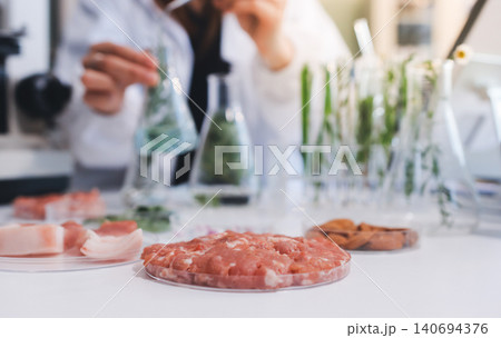 Scientists in lab coats work with plants in a modern lab, focusing on research and experimentation under bright, sterile conditions. Scientists in lab coats work with plants in a modern lab, focusing on research and experimentation under bright, sterile conditions. 140694376