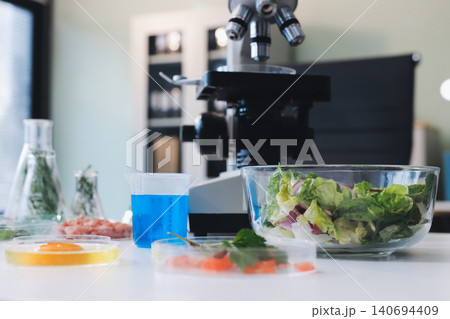 Scientists in lab coats work with plants in a modern lab, focusing on research and experimentation under bright, sterile conditions. Scientists in lab coats work with plants in a modern lab, focusing on research and experimentation under bright, sterile conditions. 140694409