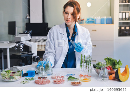 Scientists in lab coats work with plants in a modern lab, focusing on research and experimentation under bright, sterile conditions. Scientists in lab coats work with plants in a modern lab, focusing on research and experimentation under bright, sterile conditions. 140695633