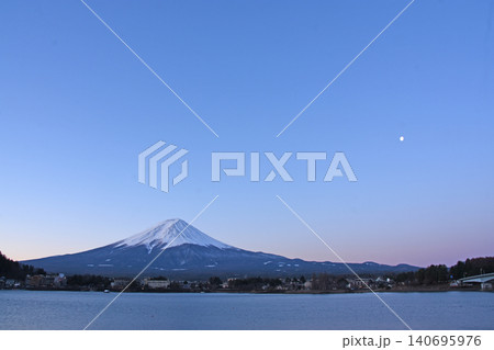 薄いピンクのビーナスベルトをバックに河口湖畔の対岸にどっしりと構える純白の冬の富士山と空に浮かぶ月 薄いピンクのビーナスベルトをバックに河口湖畔の対岸にどっしりと構える純白の冬の富士山と空に浮かぶ月 140695976