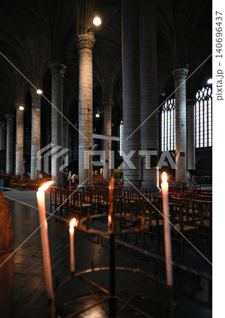 Tall Votive Candles Burning in Dark Gothic Cathedral Interior With Stone Columns 140696437