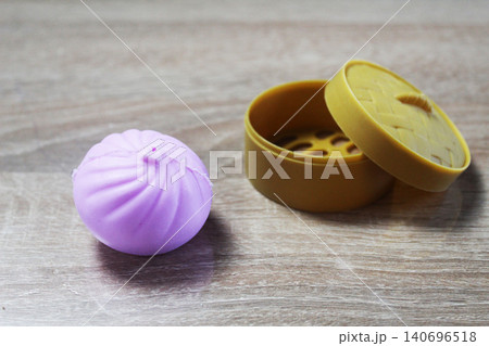 Anti-stress toy in the shape of a pink dumpling squishy lying near the box Anti-stress toy in the shape of a pink dumpling squishy lying near the box 140696518