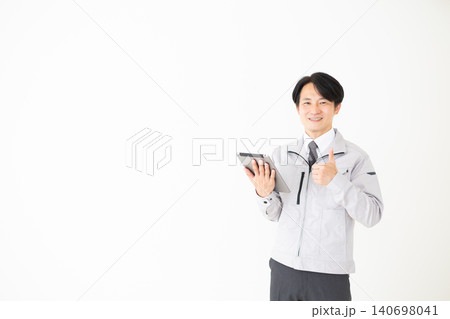タブレットを持って親指を立てるグレーの作業着のミドル男性ビジネスマン白バック タブレットを持って親指を立てるグレーの作業着のミドル男性ビジネスマン白バック 140698041