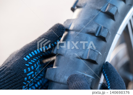 Old motorbike tire without rubber tile. Inspecting motorbike tire, replacement of old worn wheel 140698376