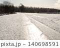 Slippery frozen road on gloomy winter day, close up. Fast change of weather, icy road, tire tracks 140698591