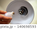 Male hand holding LED light bulb, going to replace old incandescent bulb in the office lamp, close up. Renewing and upgrading lighting in the house, energy-efficient light bulb 140698593