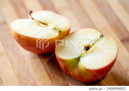 Close up of red apple cut into two halves, laying on the table. Ripe fruit, full of vitamins, ready to eat Close up of red apple cut into two halves, laying on the table. Ripe fruit, full of vitamins, ready to eat 140698602