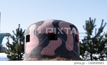 Close view of camouflaged concrete pillbox bunker painted in irregular pink and dark gray shapes with rectangular observation slits and rusted metal fittings Close view of camouflaged concrete pillbox bunker painted in irregular pink and dark gray shapes with rectangular observation slits and rusted metal fittings 140699961