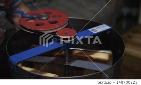 Close-up view of a mechanical belt drive with red and blue pulleys, a black rotating wheel, and metal components in a dim workshop setting with shallow depth of field 140700225