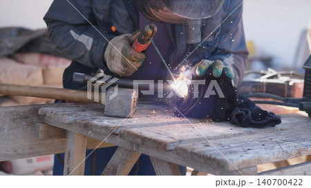 Onsite Welder Producing Bright Sparks While Repairing Metal Component On Temporary Bench, Rugged Gloves And Mask Visible, Portable Generator Powering Tool, Industrial Repair Atmosphere. Onsite Welder Producing Bright Sparks While Repairing Metal Component On Temporary Bench, Rugged Gloves And Mask Visible, Portable Generator Powering Tool, Industrial Repair Atmosphere. 140700422