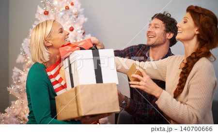 Friends, Christmas and present for celebration at tree for festive season or giving gift box, vacation or holiday. Man, women and parcel in living room for winter break or excited, bonding or love Friends, Christmas and present for celebration at tree for festive season or giving gift box, vacation or holiday. Man, women and parcel in living room for winter break or excited, bonding or love 140700666
