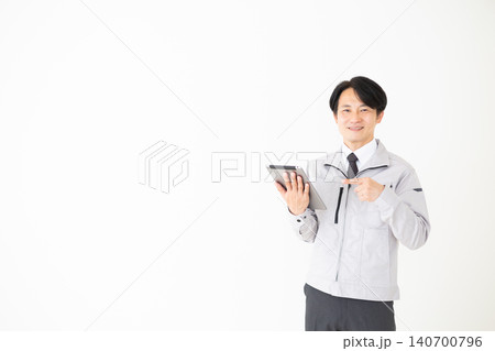 タブレットを指差すグレーの作業着のミドル男性ビジネスマン白バック 140700796