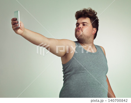 Selfie, phone and plus size man in studio posing with casual, trendy and cool outfit with stomach. Cellphone, pout and overweight male person with photography picture isolated by gray background. Selfie, phone and plus size man in studio posing with casual, trendy and cool outfit with stomach. Cellphone, pout and overweight male person with photography picture isolated by gray background. 140700842