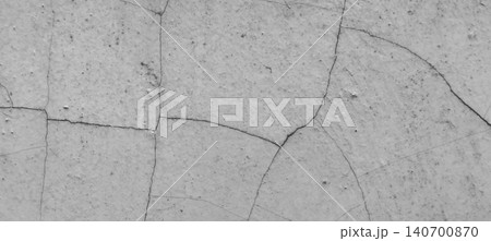 The texture of the cracked concrete wall is gray with a surface that has experienced weathering and natural damage. 140700870