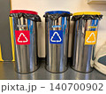 Front view of three metal recycling bins with colored lids 140700902