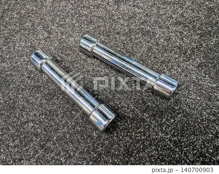 Chrome dumbbells on dark grey gym carpet background 140700903