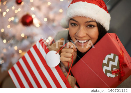 Christmas gift, happy woman and portrait in home with bag for celebration of holiday or festive season in living room. Xmas, face and smile of person with present, hat and bokeh in apartment in Spain Christmas gift, happy woman and portrait in home with bag for celebration of holiday or festive season in living room. Xmas, face and smile of person with present, hat and bokeh in apartment in Spain 140701132