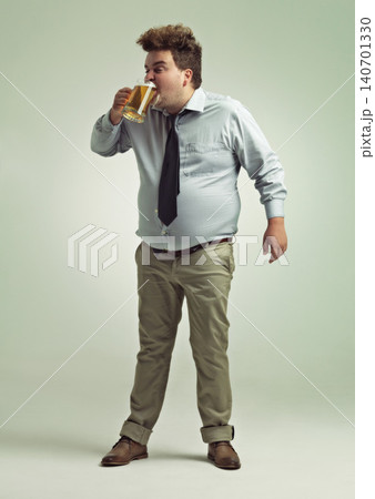 Man, face and drinking with beer for party or chug in obesity on a studio background. Young male person or plus size model with glass, mug or alcohol in satisfaction for brew or booze on mockup space 140701330