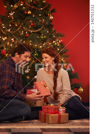 Couple, tree for Christmas and gift for holiday celebration, festive season of giving for love and commitment. Happy, gratitude and support with people at home for present, romance and relationship 140701332