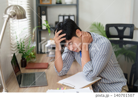 Stressed Asian man suffering from neck pain and headache at office desk Stressed Asian man suffering from neck pain and headache at office desk 140701507