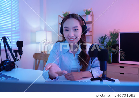 Smiling Asian woman podcaster streaming online content from home studio for engaging audience happy 140701993