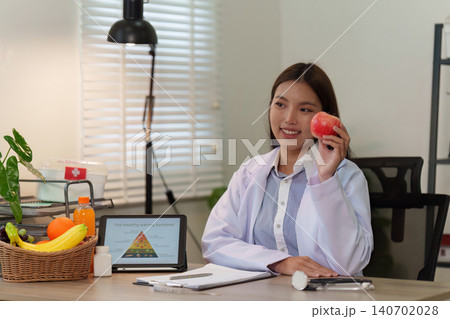 Asian woman nutritionist promoting healthy eating and wellness lifestyle with apple for medical diet advice 140702028