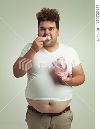 Portrait, hunger and marshmallow with plus size man in studio on gray background for unhealthy eating. Food, hungry for sweets and candy with young person with snack bag or packet for greed or belly Portrait, hunger and marshmallow with plus size man in studio on gray background for unhealthy eating. Food, hungry for sweets and candy with young person with snack bag or packet for greed or belly 140702188