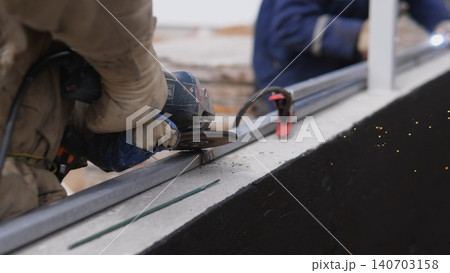Gloved Hands Tightening Bolt On Metal Beam, Construction Technician Securing Exterior Panel With Clamp And Wrench, Closeup Of Protective Gloves And Tool Interaction, Industrial Rooftop Site, Gloved Hands Tightening Bolt On Metal Beam, Construction Technician Securing Exterior Panel With Clamp And Wrench, Closeup Of Protective Gloves And Tool Interaction, Industrial Rooftop Site, 140703158