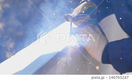 Welder Welding Steel Beam Under Bright Sparks, Closeup Of Torch And Protective Gloves, Heavy Gauge Metal, Outdoor Construction Atmosphere With Glowing Arc And Flying Particles, Focused Welder Welding Steel Beam Under Bright Sparks, Closeup Of Torch And Protective Gloves, Heavy Gauge Metal, Outdoor Construction Atmosphere With Glowing Arc And Flying Particles, Focused 140703287