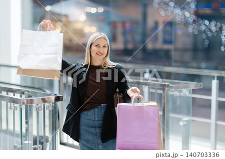 Happy woman holding shopping bags in mall 140703336