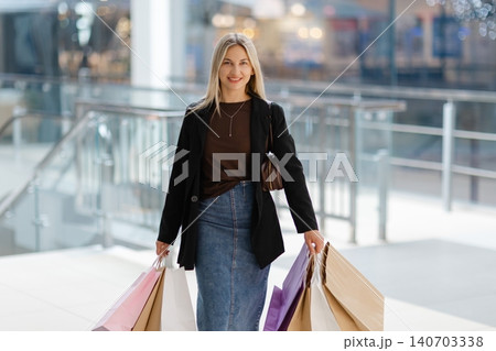 Woman holding shopping bags pointing in mall Woman holding shopping bags pointing in mall 140703338