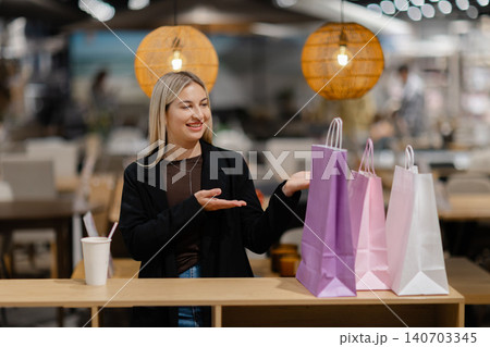 Woman presenting shopping bags showing customer satisfaction Woman presenting shopping bags showing customer satisfaction 140703345