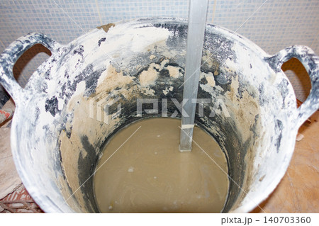 Mixing Cement and Water in Construction Tub with Stick Mixing Cement and Water in Construction Tub with Stick 140703360