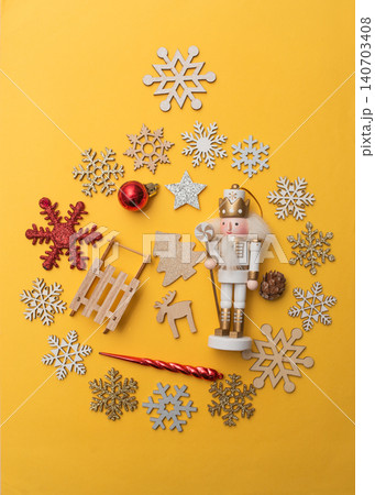 Colorful holiday-themed arrangement featuring a nutcracker, snowflakes, ornaments, and festive decorations on a vibrant yellow background, creating a joyful seasonal atmosphere 140703408