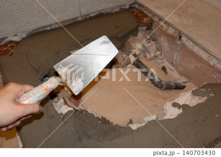Female Hand Holding Putty Knife During Shower Renovation Work 140703430