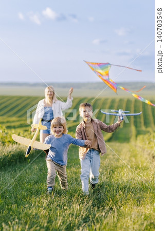 Mother and children flying kite and playing outdoors Mother and children flying kite and playing outdoors 140703548