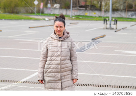 Woman standing in empty parking lot looking at camera outdoors 140703656