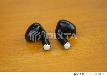 Wireless Black Earbuds on Wooden Surface with Minimal Background Wireless Black Earbuds on Wooden Surface with Minimal Background 140704064