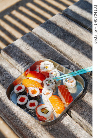 a sushi box rests on a wooden bench a sushi box rests on a wooden bench 140704133