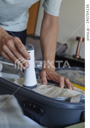 man using a vacuum pump to store clothes in a bag man using a vacuum pump to store clothes in a bag 140704136