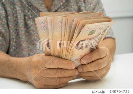 Asian elder senior woman patient holding Thai banknotes money in her hand, Cost of living and medical care. 140704723