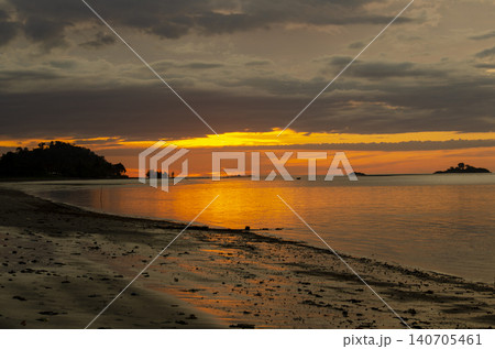 Serene beach shoreline with gentle waves and expansive blue sky showcasing a tranquil coastal landscape scene 140705461
