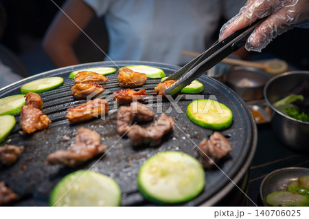Grilling Meat and Vegetables on a Hot Plate with Tongs in a Restaurant Setting Grilling Meat and Vegetables on a Hot Plate with Tongs in a Restaurant Setting 140706025