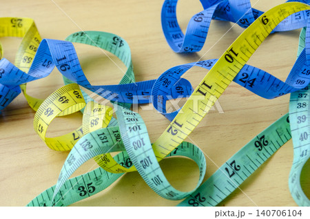 Multiple measuring tapes scattered across a wooden surface representing fitness planning and lifestyle improvement efforts 140706104