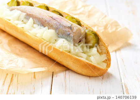 soft bun with Dutch herring fillet, onion and picked cucumber, on table. soft bun with Dutch herring fillet, onion and picked cucumber, on table. 140706139