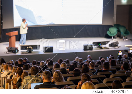 Presenter delivering business presentation on stage to large audience at conference auditorium Presenter delivering business presentation on stage to large audience at conference auditorium 140707934