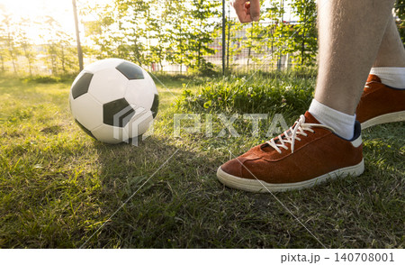 Man wearing white shorts and red sneakers about to kick a soccer ball, creating a dynamic scene and soccer background. 140708001